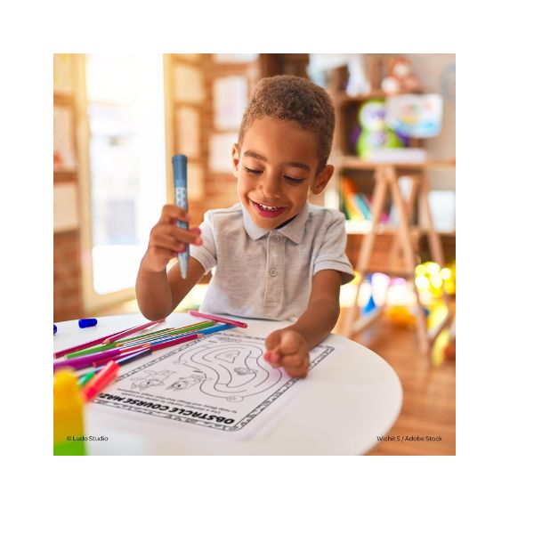 Child coloring with crayons in a bright room